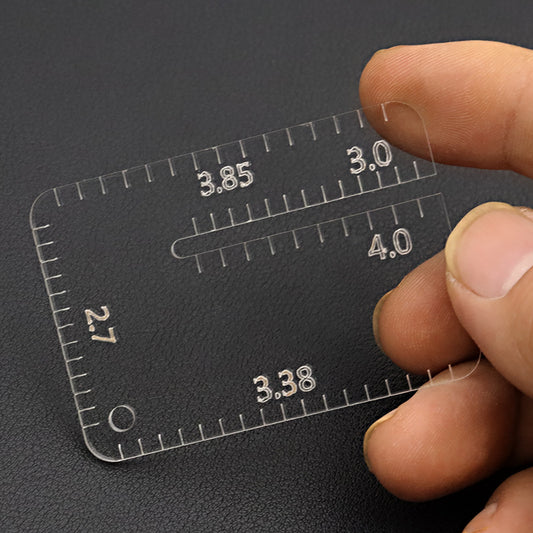 Clear stitch spacing ruler template with mm markings from 2.7 to 4.0, held between fingers