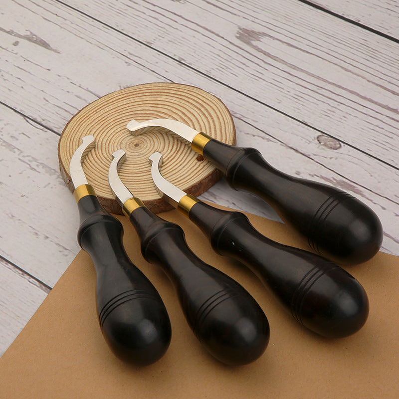 Leather edge creaser tool with dark handle and gold band, curved blade on leather strip