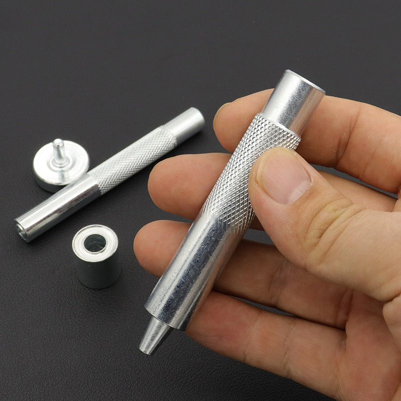Handheld grommet setter tool with base die and metal eyelet rings, close-up