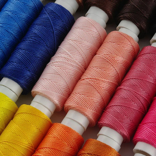 Assorted waxed round thread spools in blue, pink, coral, red, yellow, and brown