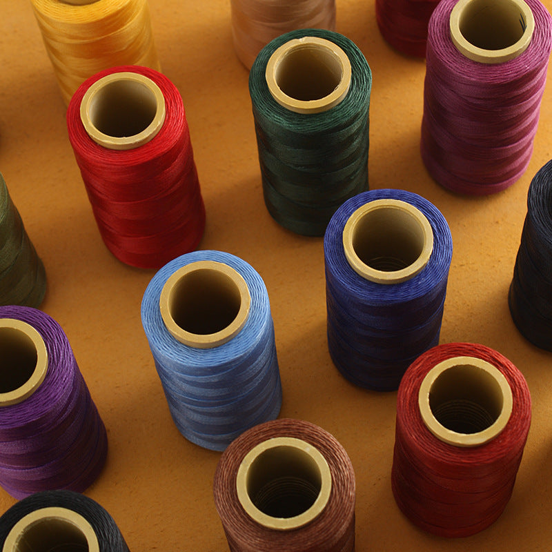 Assorted waxed polyester stitching thread spools in blue, red, green, and purple