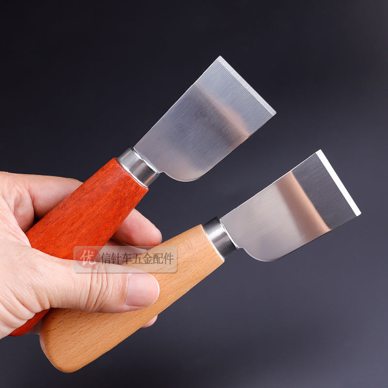 Leather skiving knife with red wood handle held in hand, mirror-finish steel blade