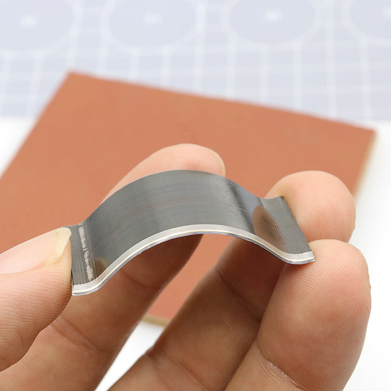 Steel corner rounding die punch held in hand, curved cutting profile with silver edge