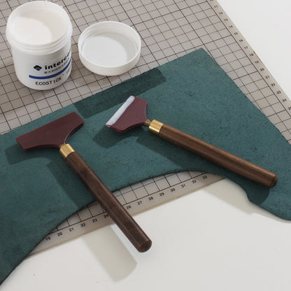 Silicone glue scraper spreader with two maroon heads, dark wood handle, and brass collar