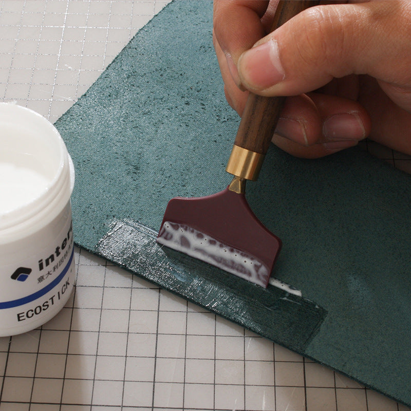 Silicone glue scraper spreader tool with dark brown wood handle and maroon rubber head