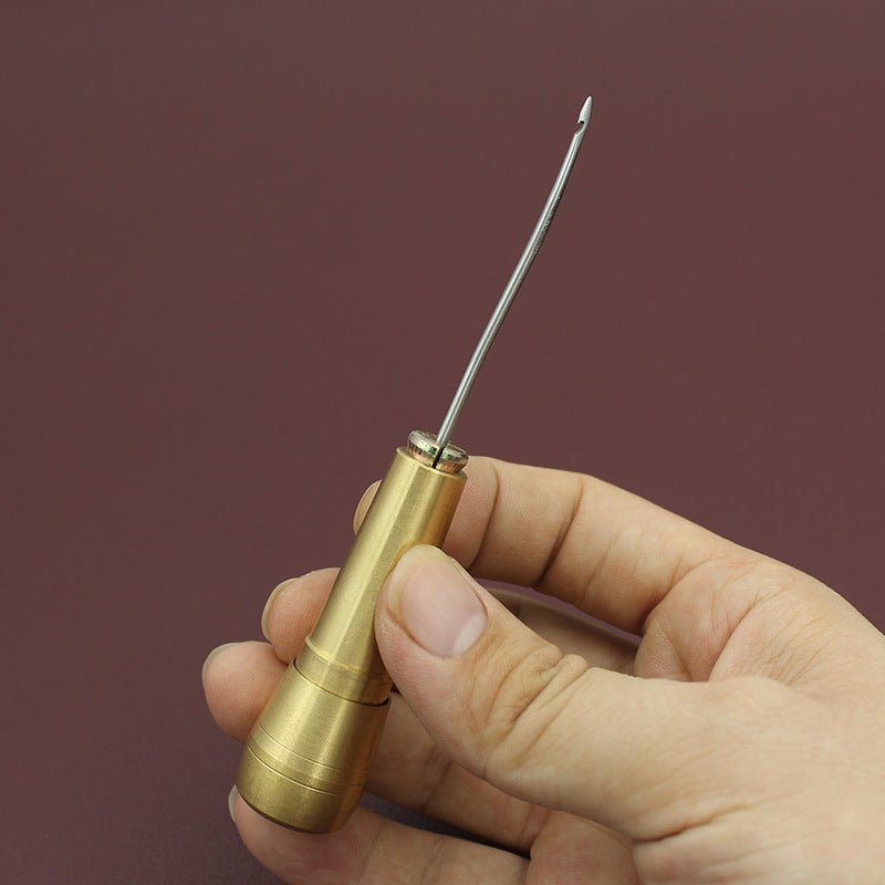 Brass awl handle with pointed awl bit, held in hand