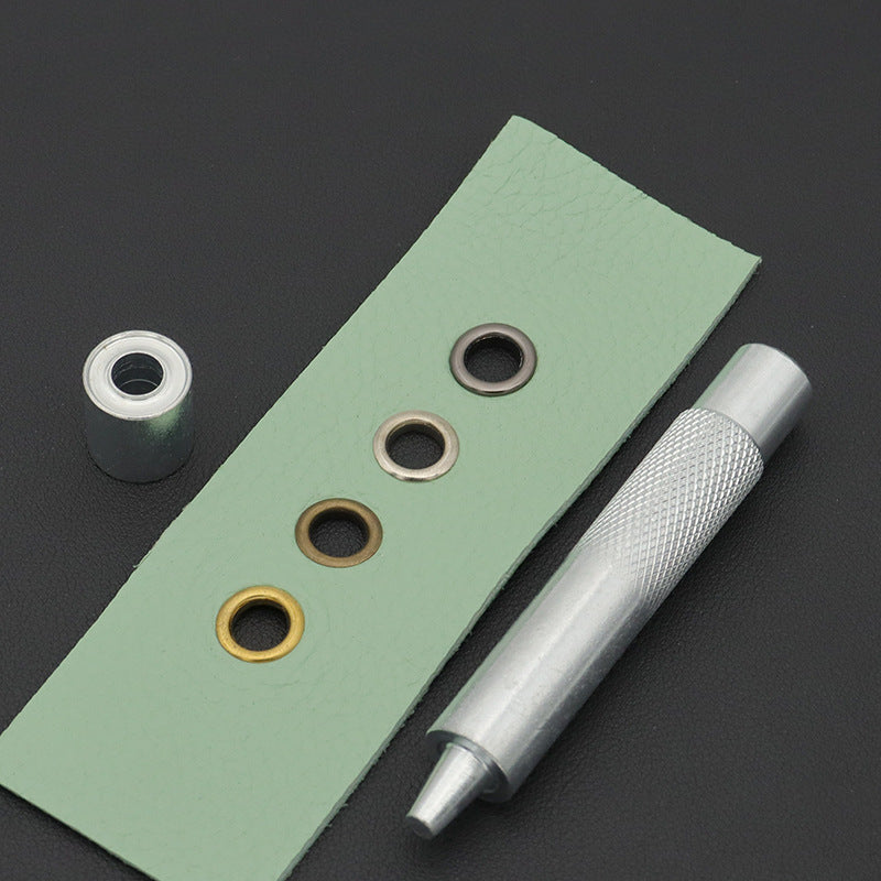 Hand grommet setter tool with base die and metal eyelet rings on green backing
