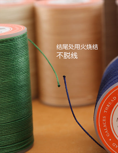 Waxed leather stitching thread spools with green and dark blue thread ends