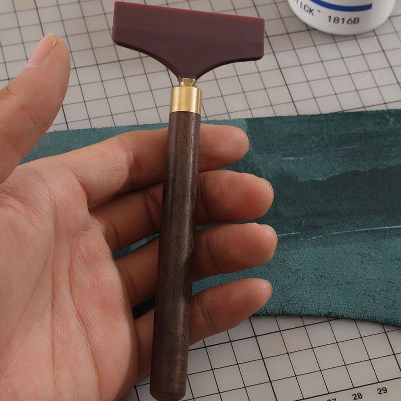Handheld silicone glue scraper spreader: dark brown wood handle with maroon rubber head