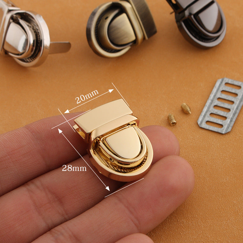 Gold metal twist-lock bag buckle with curved latch and size markings 20x28mm
