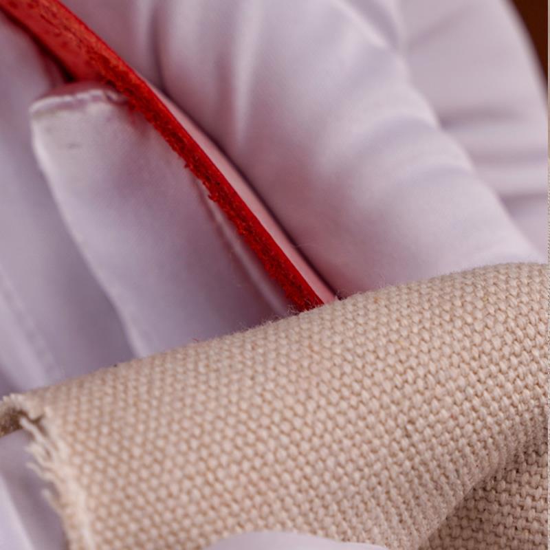 Off-white canvas polishing cloth buffing a red leather edge