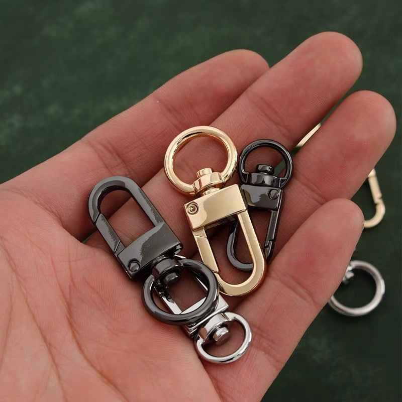 Metal swivel hook buckles held in hand, gold, gunmetal and silver bag hardware