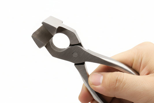 Chrome steel leather pliers with circular die, gripped in hand for pressing