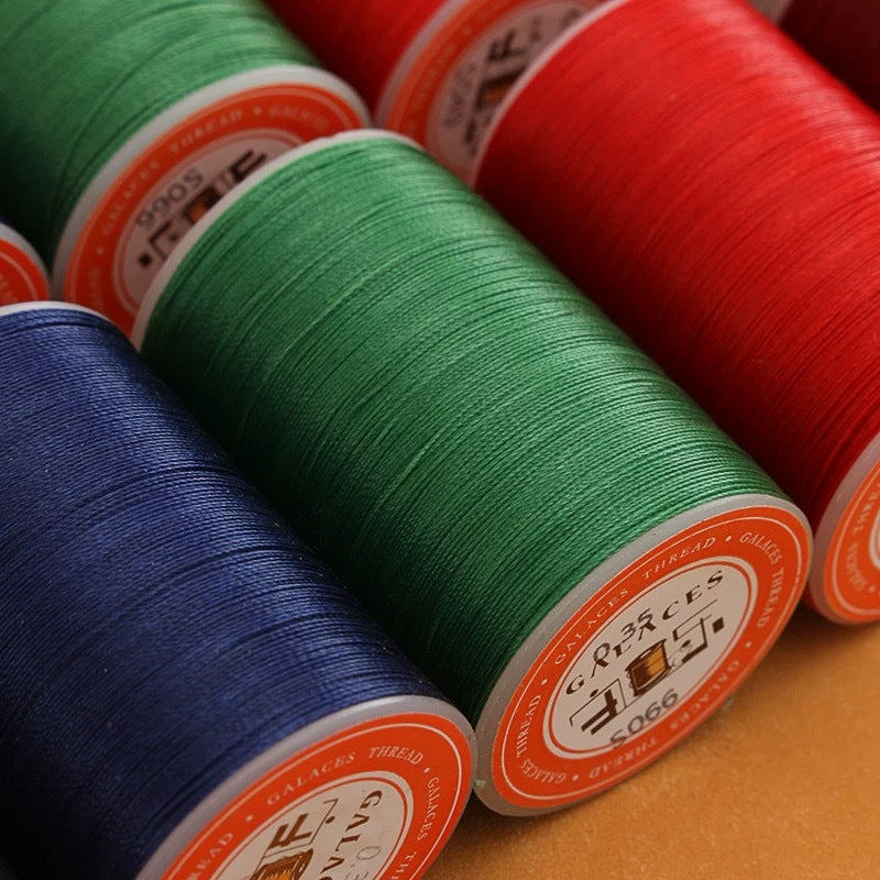 Waxed leather stitching thread spools with green, dark blue, and red rolls