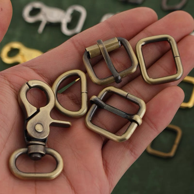 Bag hardware set shown in hand: swivel hook, square rings, and D-ring adjuster buckles