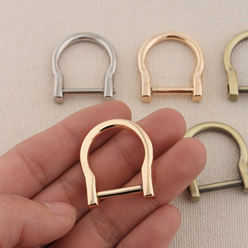 Gold-tone horseshoe D-ring buckle in hand, metal bag strap hardware