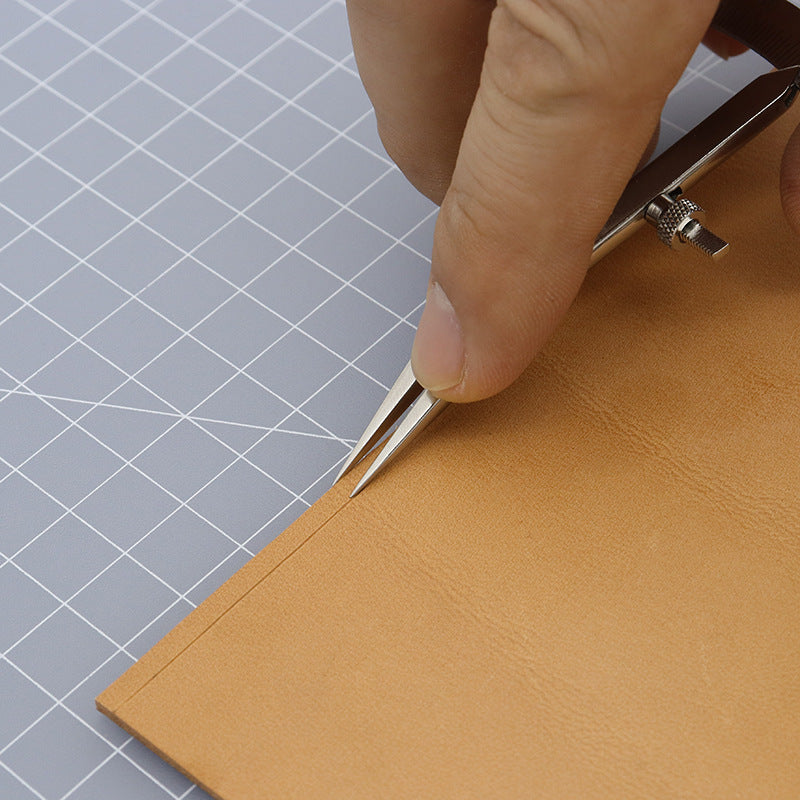 Adjustable wing divider used to mark leather on a grid cutting mat, mm scale