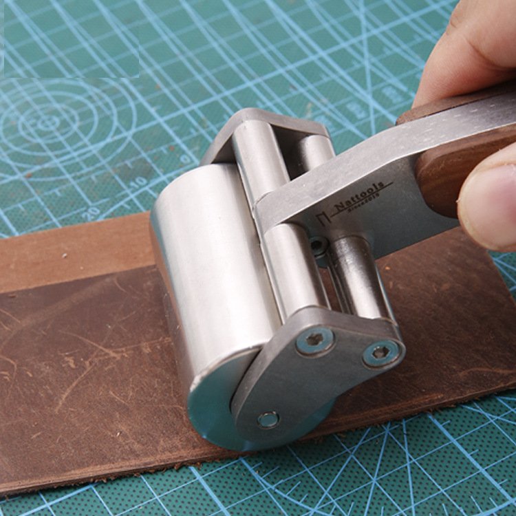 Leather roller tool with stainless steel roller and wooden handle on material