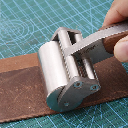 Leather roller tool with stainless steel roller and wooden handle on material