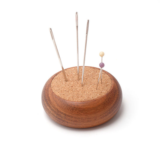 Wooden and cork pincushion with pins on a white background