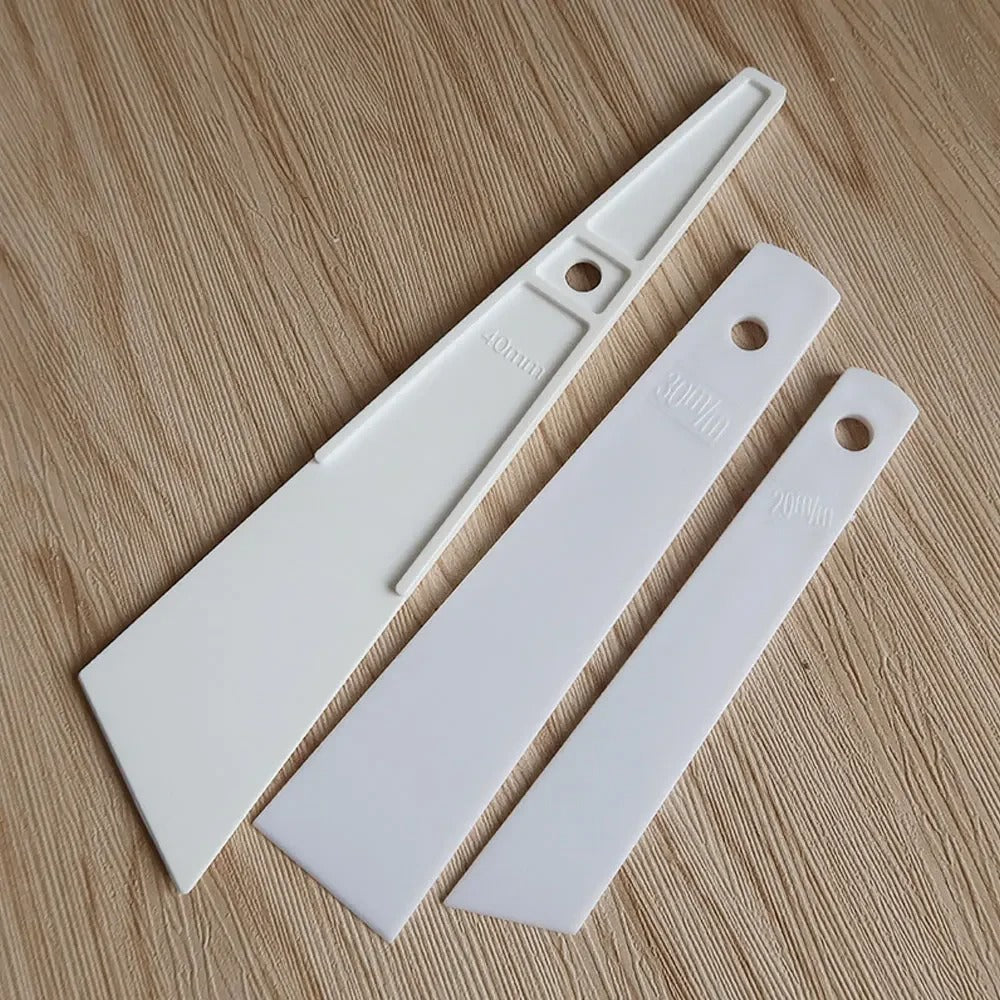 White plastic glue applicators, three pieces with hanging holes and ml markings